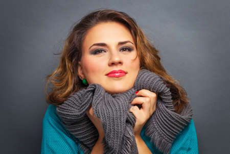 Attractive smiling woman with scarf on gray background. Fashion warm clothing concept.の写真素材