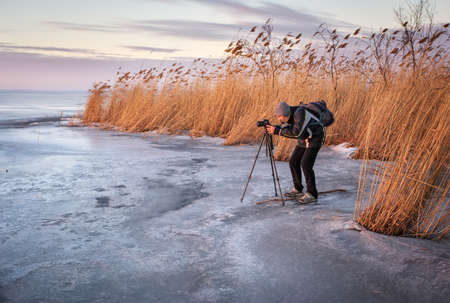 Photographer takes a picture of sunset on a frozen lakeの写真素材