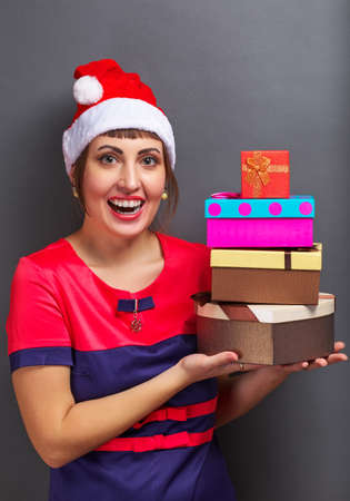 Beautiful girl in santa head with gift boxes on gray background.の写真素材