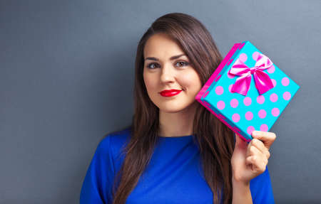 Beautiful girl holding gift box on gray backgroundの写真素材