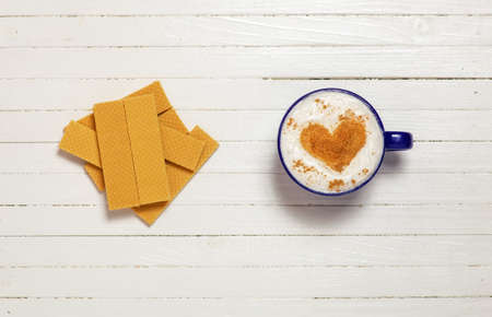 Cup of coffee with heart shape symbol and waffles on wooden white backgroundの写真素材