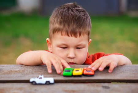 Little boy plays with colorful toy cars. Child playing with autosの写真素材
