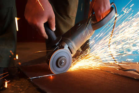 A worker using a grinder cut metal.