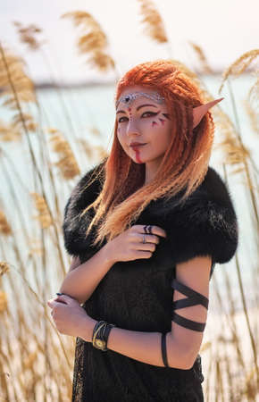 Elf women with fiery hair on nature. Beautiful young fantasy style girl. Cosplay characterの写真素材