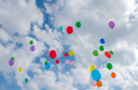 Lots of colorful balloons flying on cloudy blue sky
