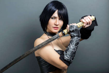 Beautiful woman-warrior with sword on grey background.の写真素材