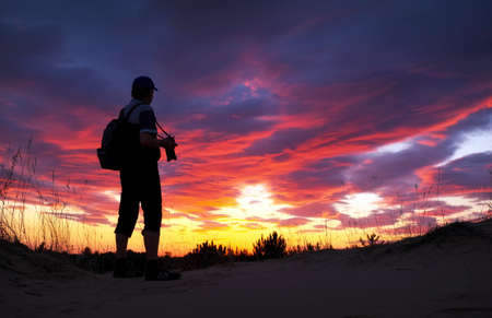 Silhouette of photographer with his camera during sunsetの写真素材