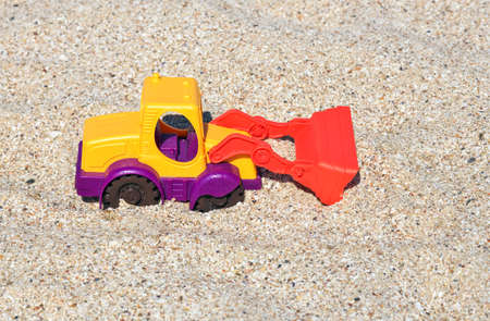 The excavator toy on the beach. Children play in the sand