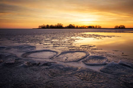 Beautiful Winter landscape with frozen river, reeds and sunset sky. Composition of nature. の写真素材