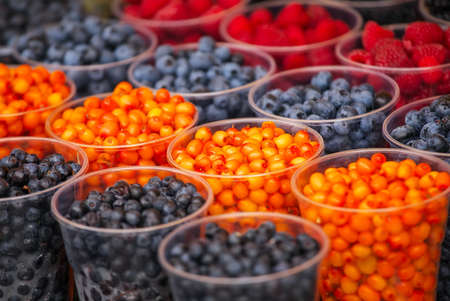 Delicious fruits in plastic cups. Colorful sweet berries closeup in the market