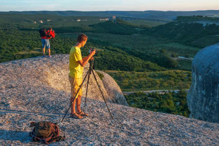 Two photographers takes pictures of nature on the rock in the evening.