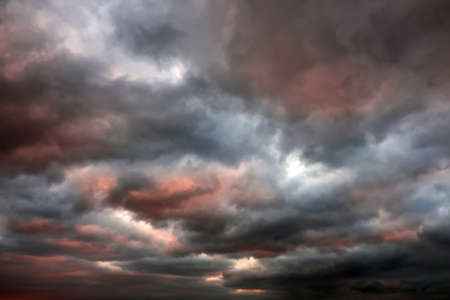 Gray clouds sky background with red light from sun.の写真素材