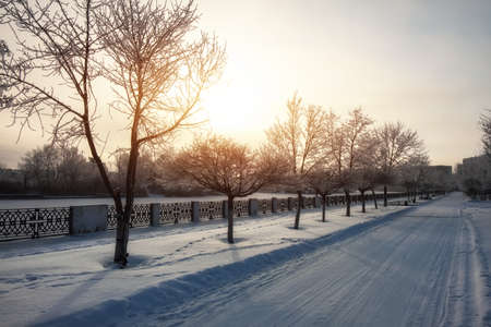 Winter snow-covered city landscape. Beautiful sky with a bright sun. Road in the snow