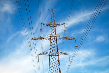 A high voltage power pylons against blue cloudy sky 