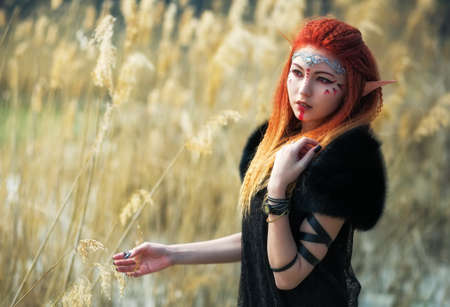 Elf women with fiery hair on nature. Beautiful young fantasy girl. Cosplay character