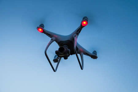 Drone is flying in the blue sky at sunset time. Modern technological background - silhouette of flying machineの写真素材