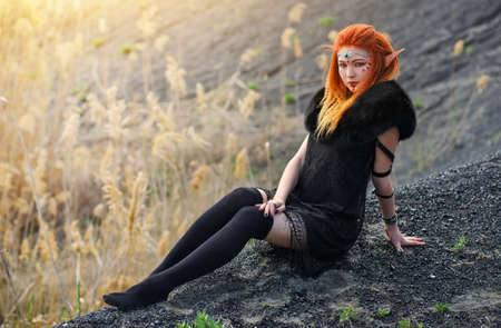 Elf women with fiery hair on nature. Beautiful young fantasy girl. Cosplay character