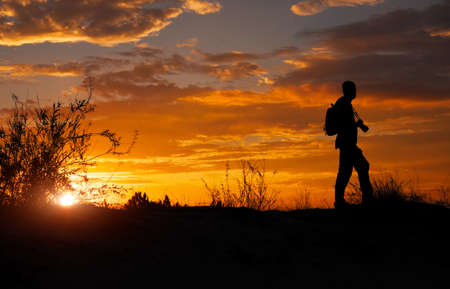 Silhouette of photographer with his camera during sunset