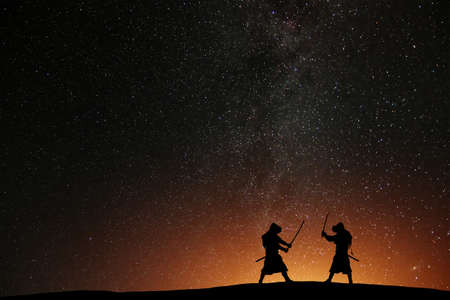 Silhouette of two samurais against the starry sky. Deadly warriors with swordsの写真素材