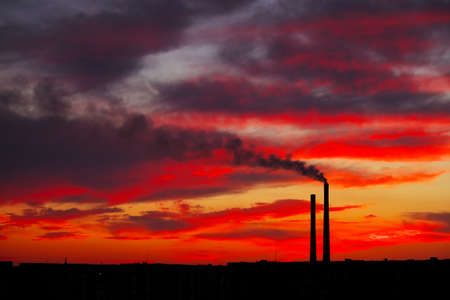 Colorful Magic Sunset. Roofs of city houses during sunrise. Dark smoke coming from the thermal power plant pipe.の写真素材