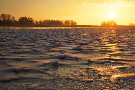 Winter landscape with frozen lake and sunset fiery sky. Composition of nature.