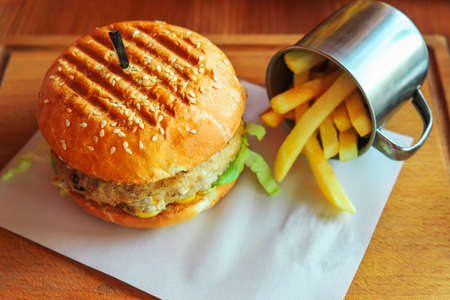 Hamburger with cheese and chop and a cup of deep fried potatoesの写真素材