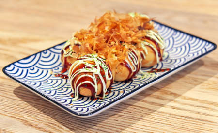 Takoyaki is a ball-shaped Japanese snack made of a wheat flour-based batter and cooked in a special molded pan. Dish from Japan (Osaka). Famous street food.の写真素材