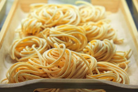 Uncooked pasta closeup in on wooden tray in the shop window. Italian foods concept of spaghetti and menu designの写真素材