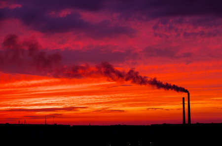 Colorful Magic Sunset. Roofs of city houses during sunrise. Dark smoke coming from the thermal power plant pipe.の写真素材