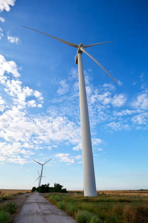 Wind turbines and agricultural field on a summer cloudy day. Energy production, clean and renewable energy.の写真素材