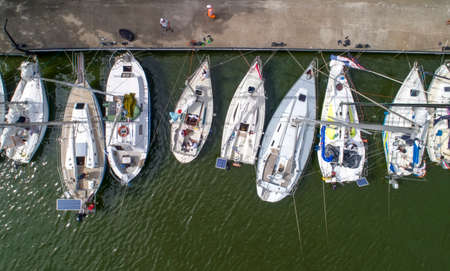 Pier with boats, marina lot. Aerial top view from drone. Green water due to seaweedの写真素材