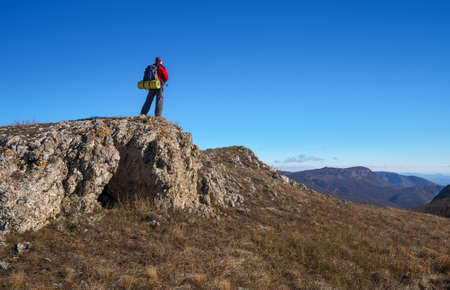 Photographer on top of the mountain in autumn. Traveler with backpack enjoying a view from the mountain top

の写真素材