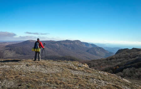 Photographer takes pictures on top of the mountain in autumn. Traveler with backpack enjoying a view from the mountain top

の写真素材