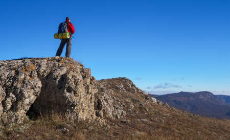 Photographer on top of the mountain in autumn. Traveler with backpack enjoying a view from the mountain top

の写真素材