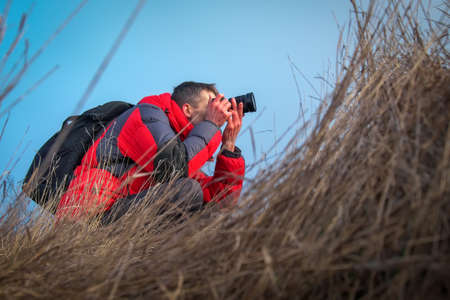An experienced photographer takes pictures in nature. A professional video maker shoots scenes in...