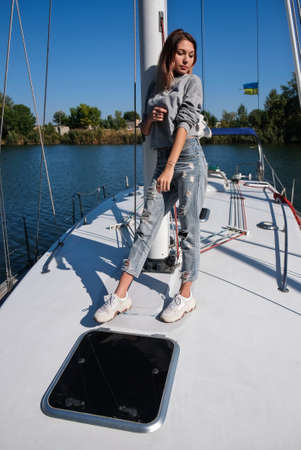 Beautiful young woman posing on yacht. Model is sailing on board.