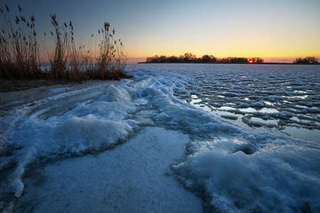 Sunrise and frozen river. Beautiful winter landscape with lake in morning time. Daybreakの写真素材
