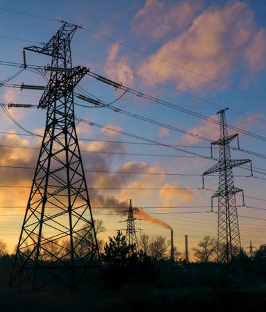 High-voltage power lines during fiery sunriseの写真素材
