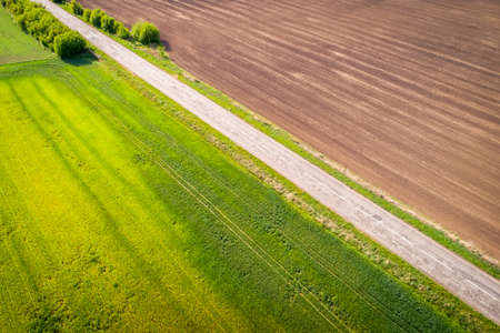 Aerial view of agricultural fields and broken patched road. Natural grass.の写真素材