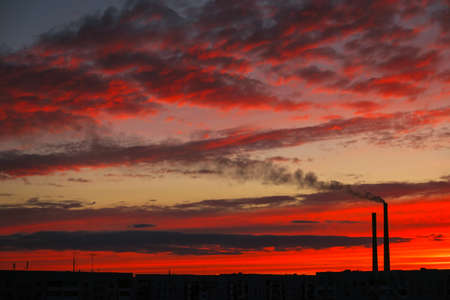 Colorful Magic Sunset. Roofs of city houses during sunrise. Dark smoke coming from the thermal power plant pipe.の写真素材