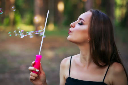 A happy girl blowing soap bubbles in summer parkの写真素材