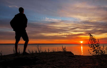 Young man standing at sunset. Sea in the morning.の写真素材