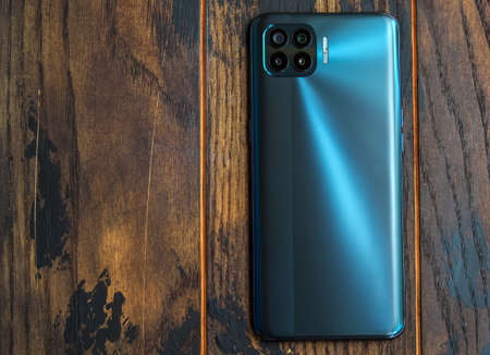 Mobile phone with holographic design with four cameras on a wooden background