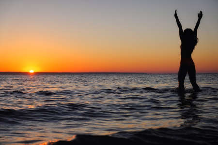 The girl swims in the sea, splashes in the water at sunset. Relaxation and happy pastime. Summer...