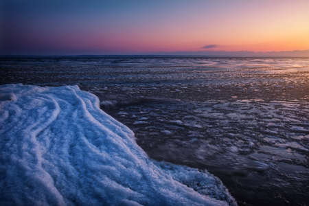 Natural Winter landscape on seashore during sunset. Ice and sunset sky.の写真素材