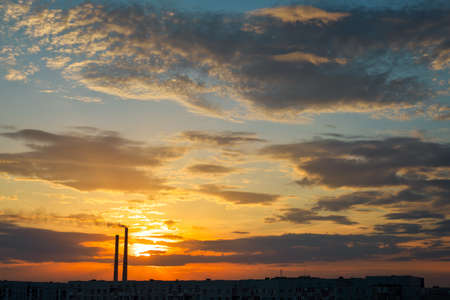Colorful Magic Sunset. Roofs of city houses during sunrise. Dark smoke coming from the thermal power plant pipe.の写真素材