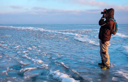A photographer takes pictures of landscapes on ice in winter. Traveler Adventures.の写真素材
