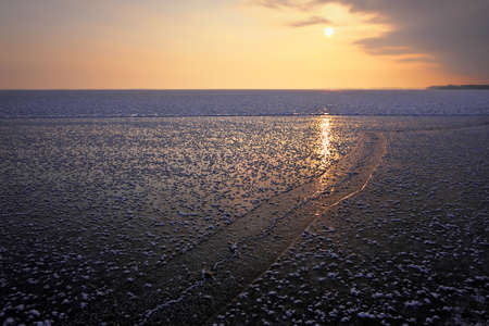 Natural Winter landscape on seashore during sunset. Ice and sunset sky.の写真素材