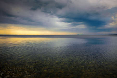 Amazing dramatic landscape. Dramatic dark clouds during sunset at sea.の写真素材