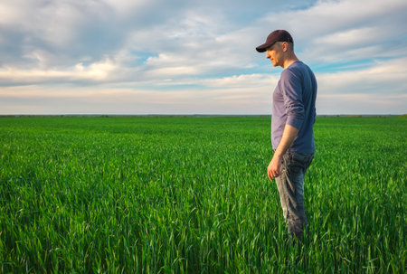 Handsome farmer. Young man walking in green field. spring agriculture.の写真素材